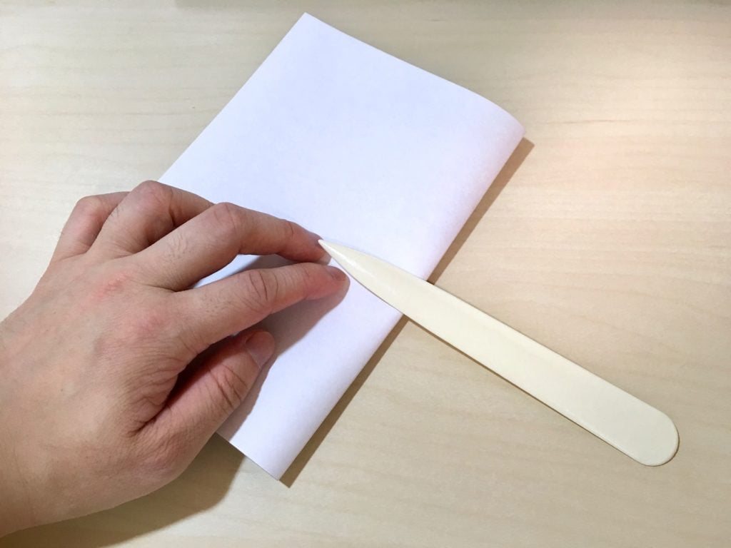 ヘラを使用して、厚紙を折っているところ