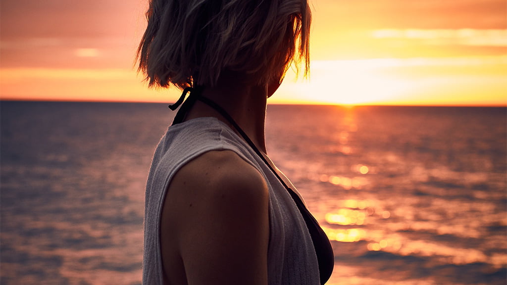 日が沈む海を眺める女性